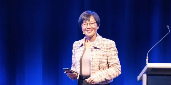 women on stage smiling and presenting with mobile in hand 