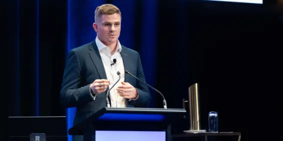 Man standing behind lectern presenting.