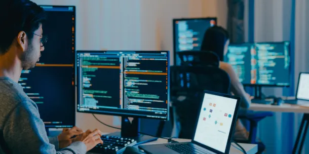 A worker typing in code on various screens