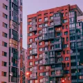 A cluster of apartment buildings in the evening, with street lights lit up.