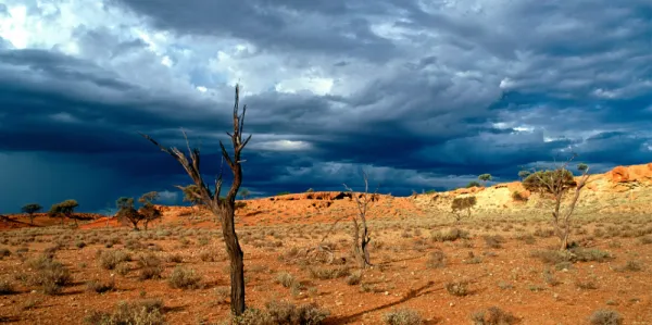 Harsh Australian outback juxtaposed to a dark, stormy sky.