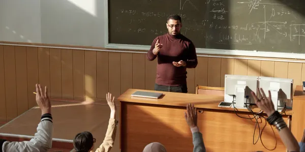 Male lecturer out front of class teaching university students