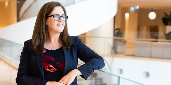 Actuary leaning on glass looking out and smiling