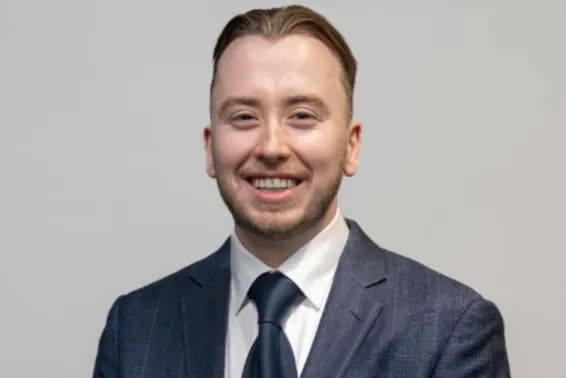 Male looking at camera smiling in steel blue suit and tie