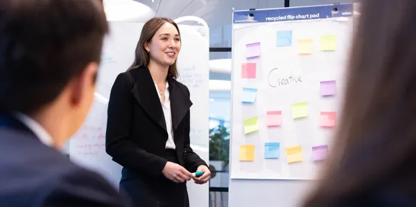 Actuary standing in front of butchers paper with post it notes brainstorming