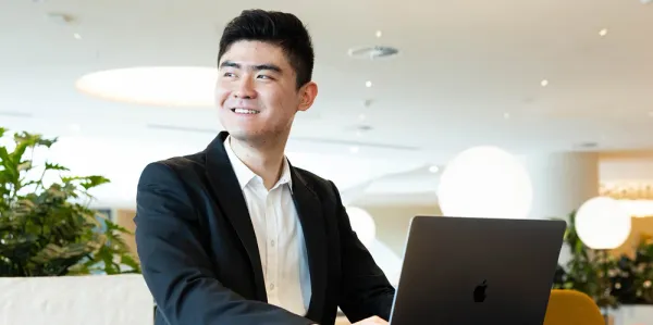 Male actuary wearing a suit typing on a laptop and smiling