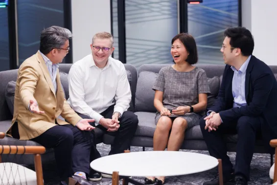 Four business people sitting casually on a large lounge chatting and laughing