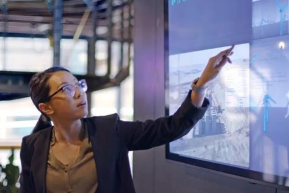 Business woman with black hair in pony tail pointing at screen and talking