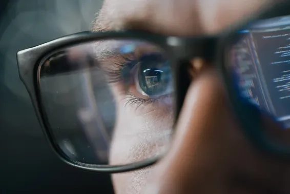 Close up of man wearing glasses with reflection of code in background