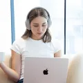 Women in white tshirt with white headphones looking down to a computer