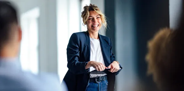 Woman standing up in front of meeting holding ipad smiling