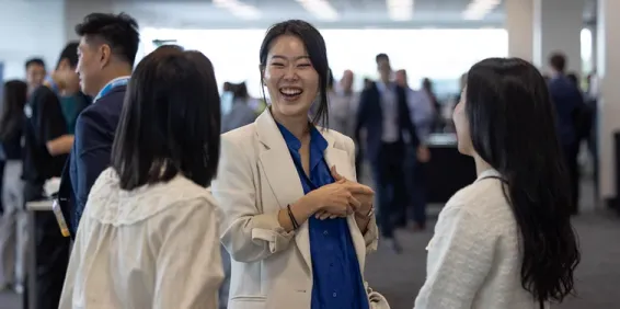 Three female actuaries talking and networking at a busy conference