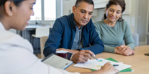 A couple sit at the kitchen table with an insurance agent as plan for the future