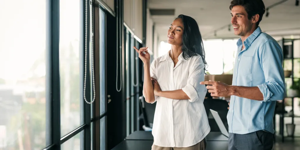 Professional woman and man looking out window.
