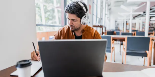 Mid adult man working using laptop at library.