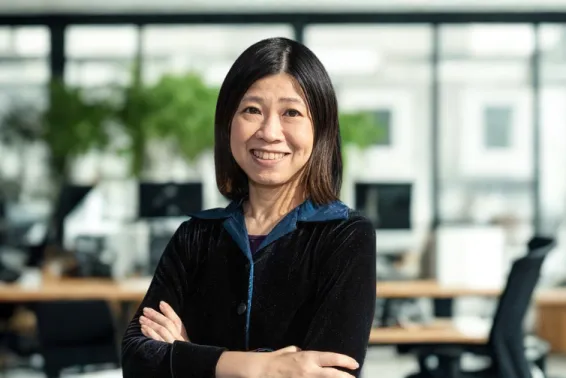 Female standing in office smiling with arms crossed.