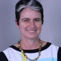 Portrait photo of Jennifer Lang in top with white and yellow colours and black trim and gold necklace