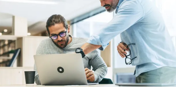 A man showing his colleague something on his computer