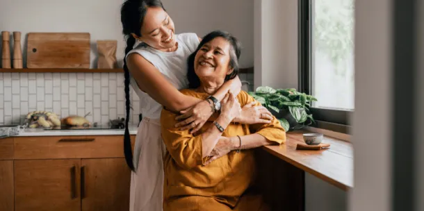 Two women embracing each other with a warm hug in the kitchen