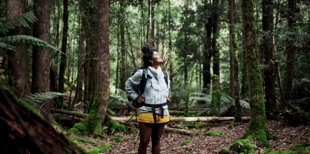 Woman on a trek through the bush, looks up for a moment with a smile