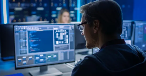 Man working at computer, reviewing coding.