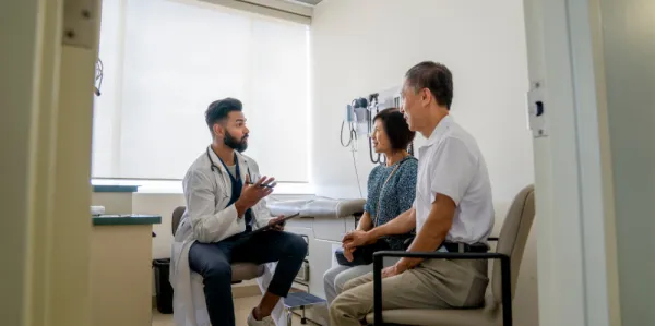 Young doctor delivering results to two patients in his room.