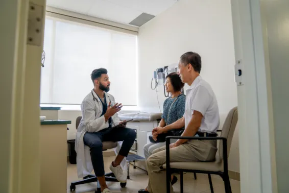 Young doctor delivering results to two patients in his room.