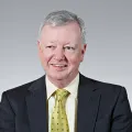 Portrait photo of Michael Rice with black suit, lemon shirt and yellow tie with black specks