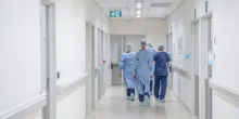 View from behind of four doctors in hospital corridor walking
