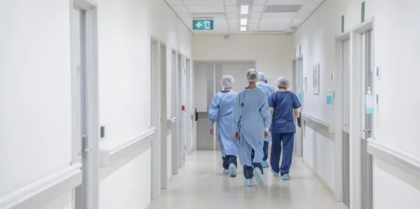 View from behind of four doctors in hospital corridor walking