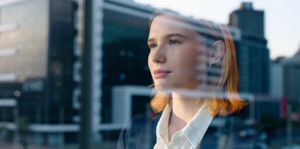 A business woman, looking out the window, reflecting.