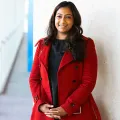Actuary in a red coat standing against a wall