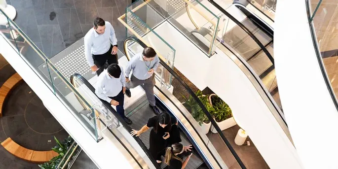 Four people walking down an escalator