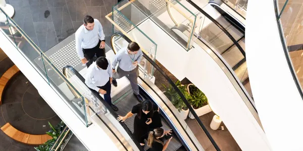 Four people walking down an escalator