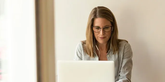 Woman with blonde hair typing on a laptop