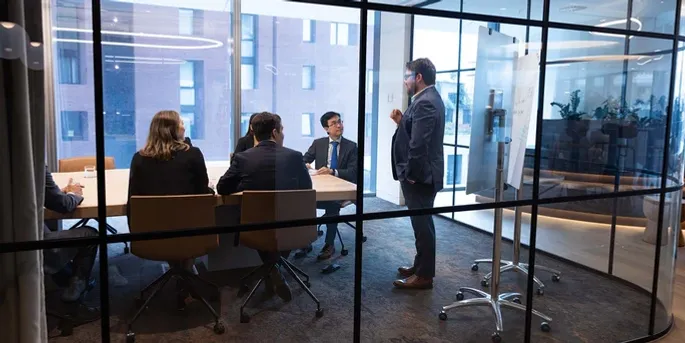 Actuary teaching other actuaries sitting around a board room table