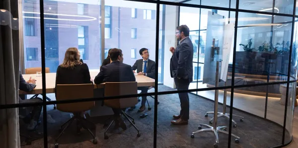 Actuary teaching other actuaries sitting around a board room table