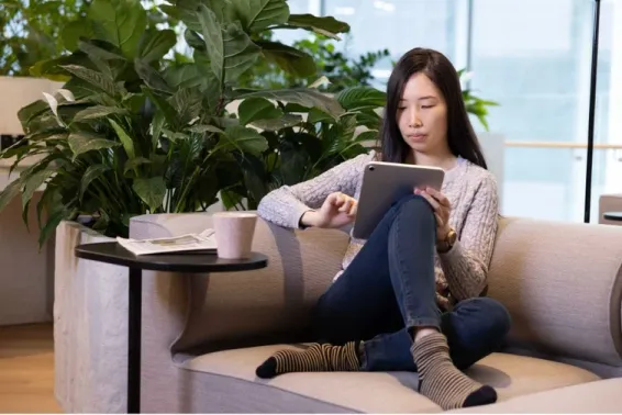 Woman on couch using tablet device