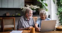 Senior couple talking about home finances and using the laptop at home.