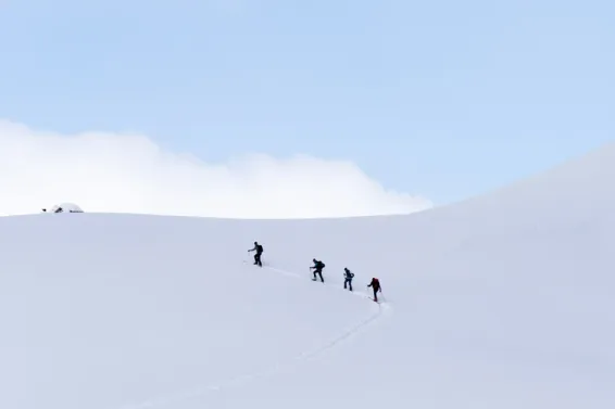 Four people walking to the top of a snow mountain