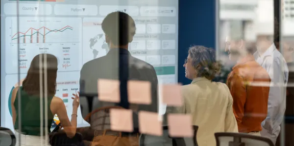 A collective group of co-workers analysing data on a big screen.