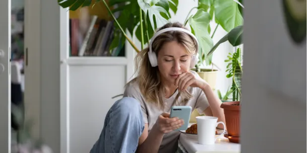 Women listening to podcast at home.