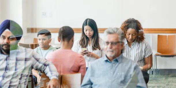 A multiracial, multigenerational group of people sit in the clinic waiting room