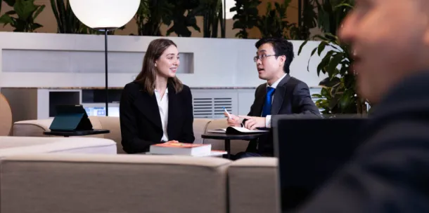 A male and female colleague speaking in a casual setting.