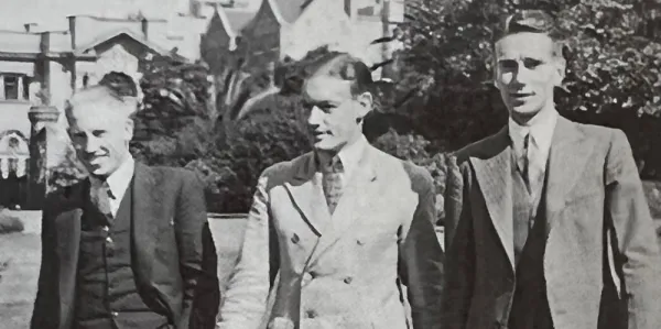 Black and white, vintage image of three men in suits standing outside.