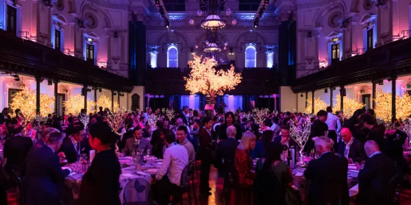 Function room full of people sitting at round tables and dining.