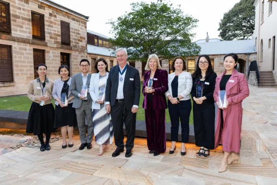 Official photo featuring 7 women and 2 men standing outside holding awards and smiling.
