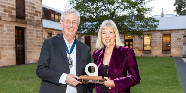 man and woman stand smiling holding a trophy