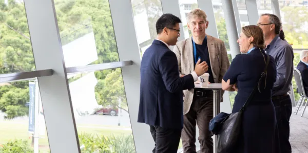Group of business people talking around a table near a floor to ceiling window.