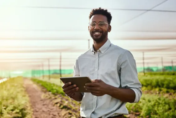 Man standing in a field of crops holding iPad